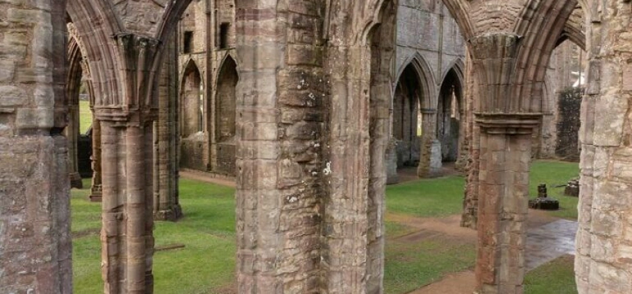 Cardiff Castles Guided Sightseeing Tour | Ruins of an ancient stone abbey with archways and green grass.