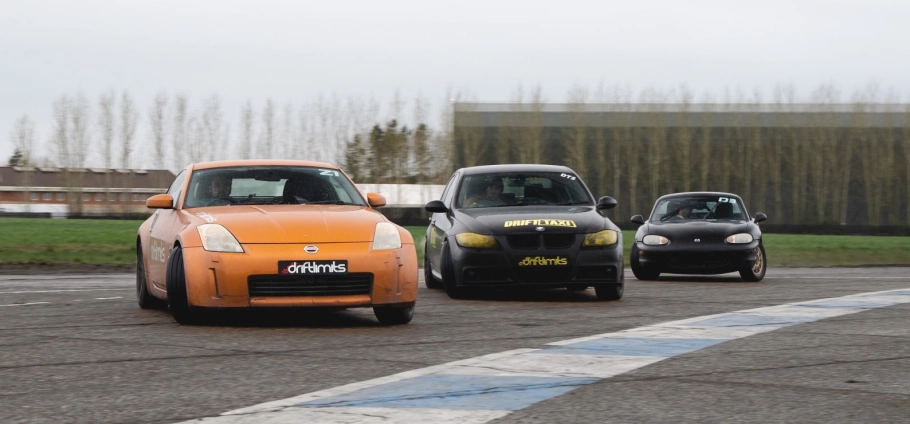 Ultimate Motorsports Race Day Experience in London | Three modified cars racing on a track with Drift Limits branding.