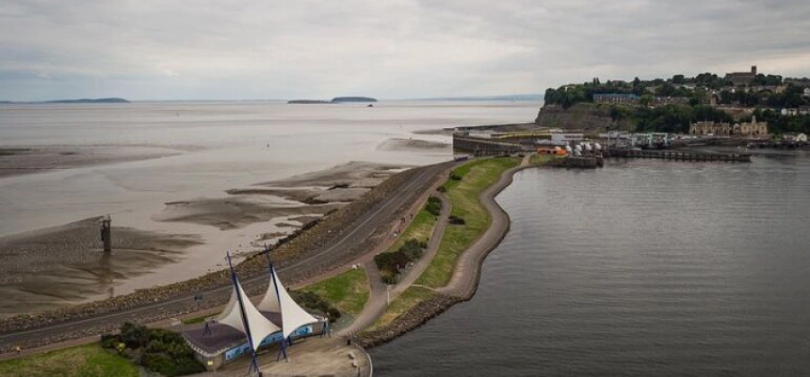 Cardiff Bay Historic Architecture Guided Tour | Aerial view of a coastal town with a pier, waterfront paths, and a unique tent-like structure near the shoreline.