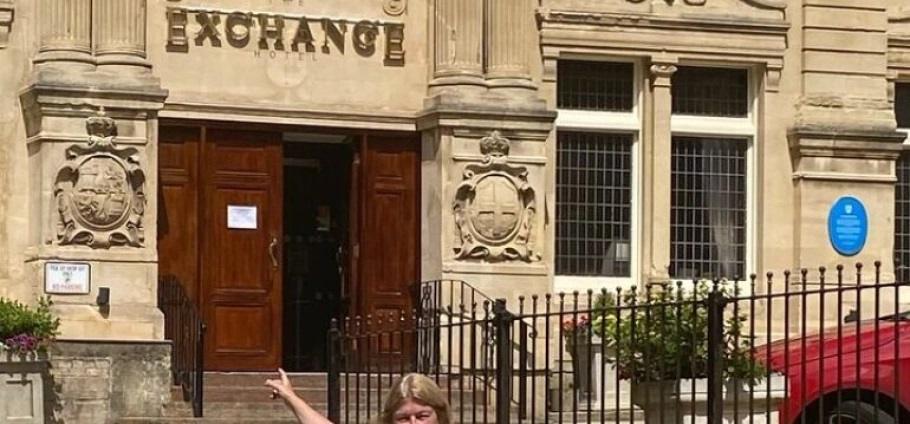 Cardiff Bay Historic Architecture Guided Tour | Person standing in front of the historic Exchange Hotel with ornate architecture and a blue plaque.