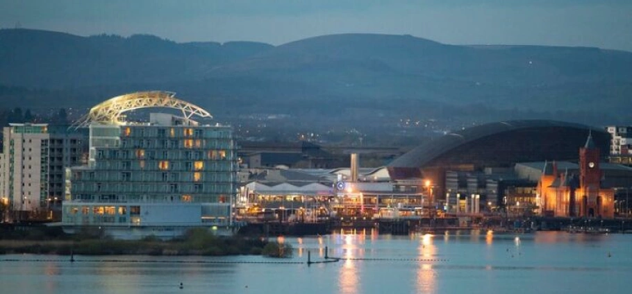 Cardiff Bay Historic Architecture Guided Tour | Cardiff Bay at dusk with illuminated buildings reflecting on the water, including the Wales Millennium Centre and Pierhead Building.