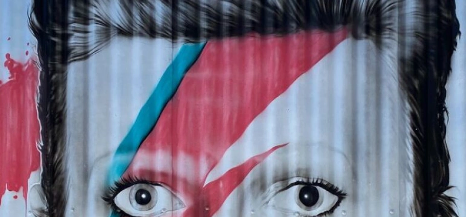 150 Minute David Bowie Trivia Tour | Street art mural featuring a face with a red and blue lightning bolt across the eyes.