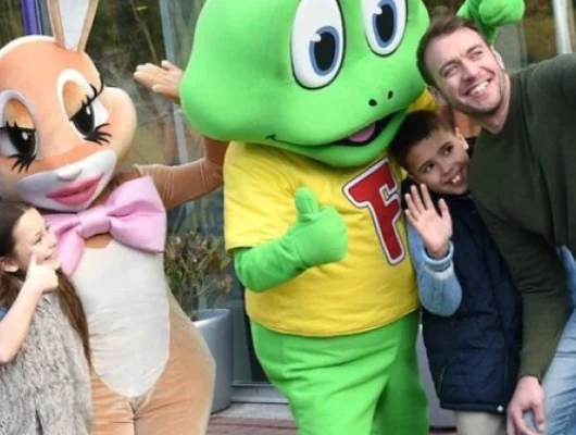 Family posing with cartoon character mascots at Cadbury World Birmingham