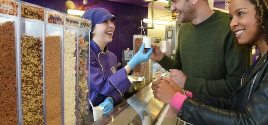 Customers sampling different chocolate options at Cadbury World Birmingham served by a smiling employee.