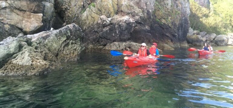 Torquay Guided Sea Kayaking Tour | People kayaking at the base of rocky cliffs.