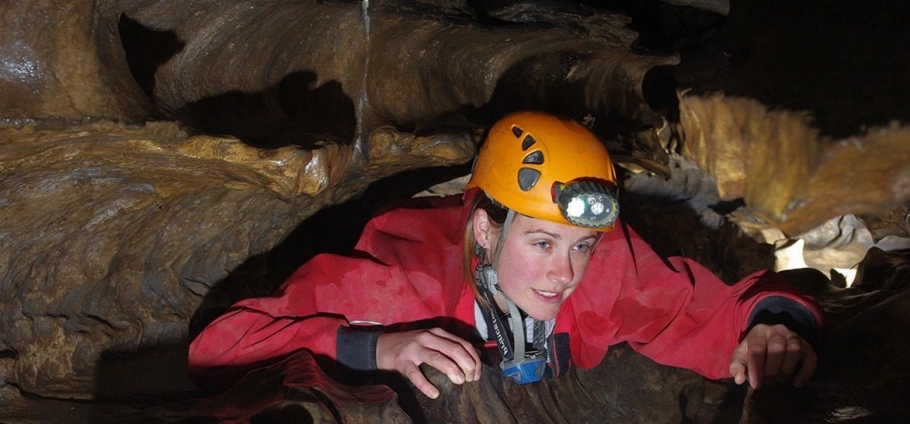 Glamorgan Caving Adventure: a young girl lying down in a cave.