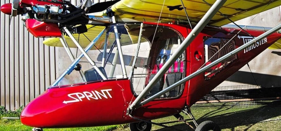 Microlight Flying Experience | A red ultralight aircraft on the ground with the word "SPRINT" written on its side.