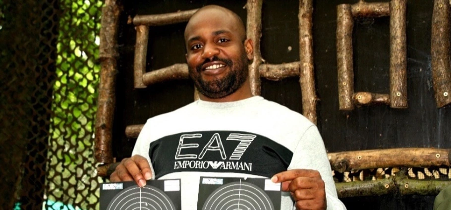 Man holding two target sheets and smiling at Rifle Shooting Experience Birmingham.