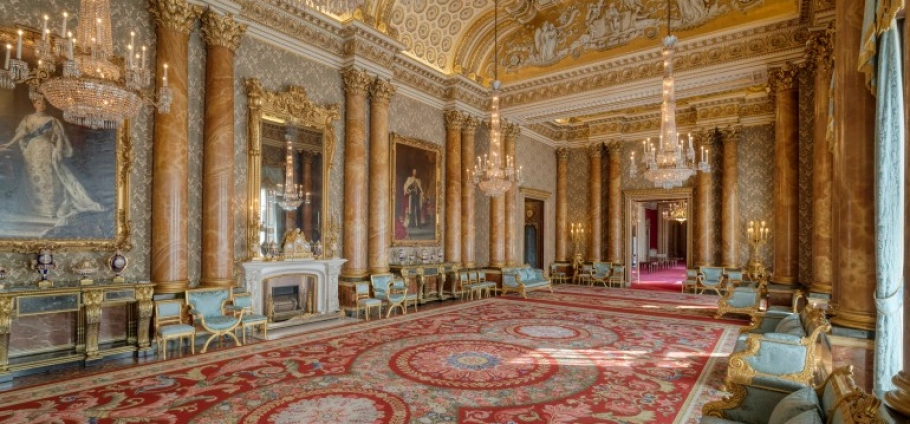 Buckingham Palace with Afternoon Tea for Two | Luxurious palace interior with ornate chandeliers, grand paintings, marble columns, and an intricately designed red carpet.