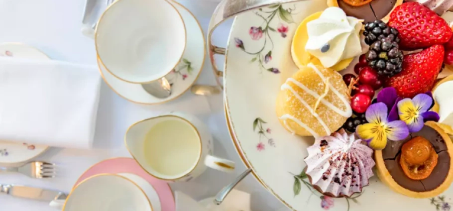 Buckingham Palace with Afternoon Tea for Two | Elegant afternoon tea setup with floral china, assorted pastries, fresh berries, and decorative flowers.