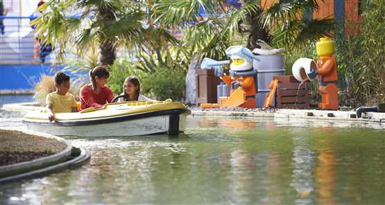 LEGOLAND Windsor Resort | Children enjoying a boat ride at Legoland theme park with Lego figures in the background.