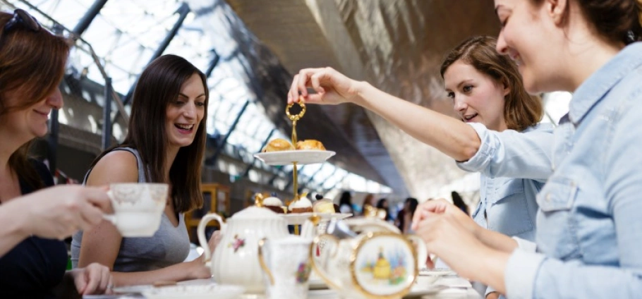 Cutty Sark Afternoon Tea and Boat Tour for Two | Group of women enjoying afternoon tea with pastries in a modern cafe.