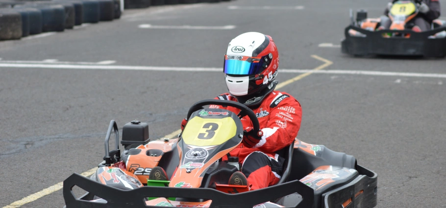 Go-kart racer in red suit and helmet driving on track