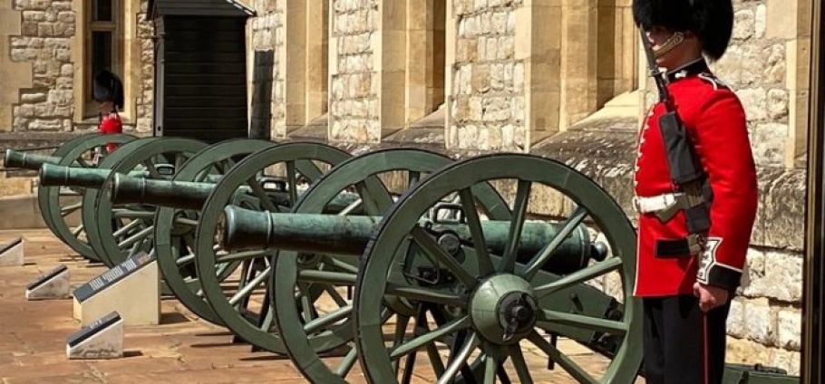 Westminster Abbey and Tower of London Tour | British guard in red uniform standing beside historic cannons at the Tower of London