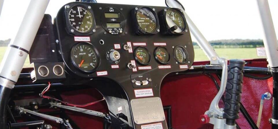 Small aircraft cockpit with control panel, various gauges, and levers.