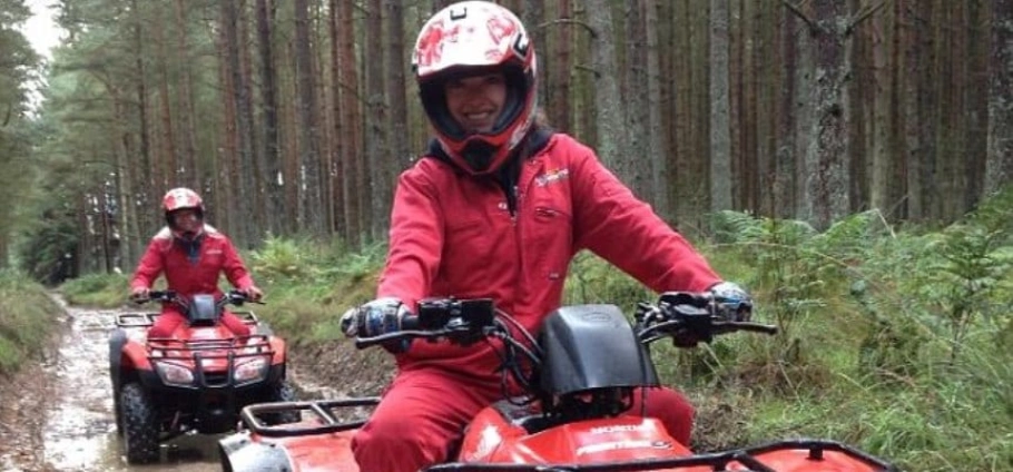 Northumberland Quad Bike Trek | Two people riding red ATVs through a forest trail.