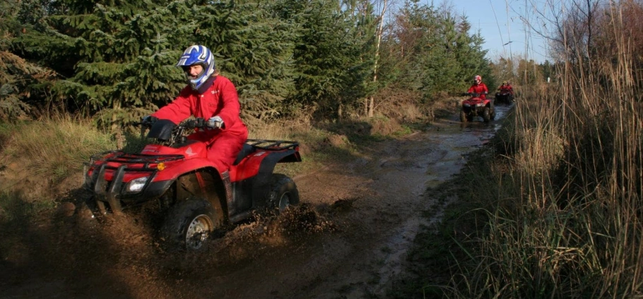 Northumberland Quad Bike Trek | Group of people riding ATVs through a muddy forest trail