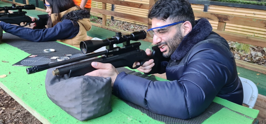 Man aiming rifle at rifle shooting Birmingham with safety glasses and winter jacket.