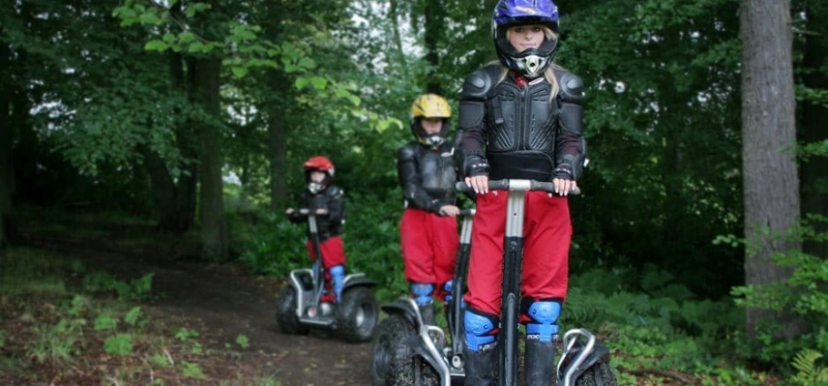 Northumberland Segway Safari | Children riding Segways in a forest wearing helmets and protective gear