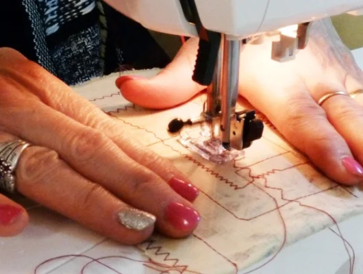 Stitch Class in Brighton | Close-up of hands using a sewing machine to stitch fabric with intricate patterns