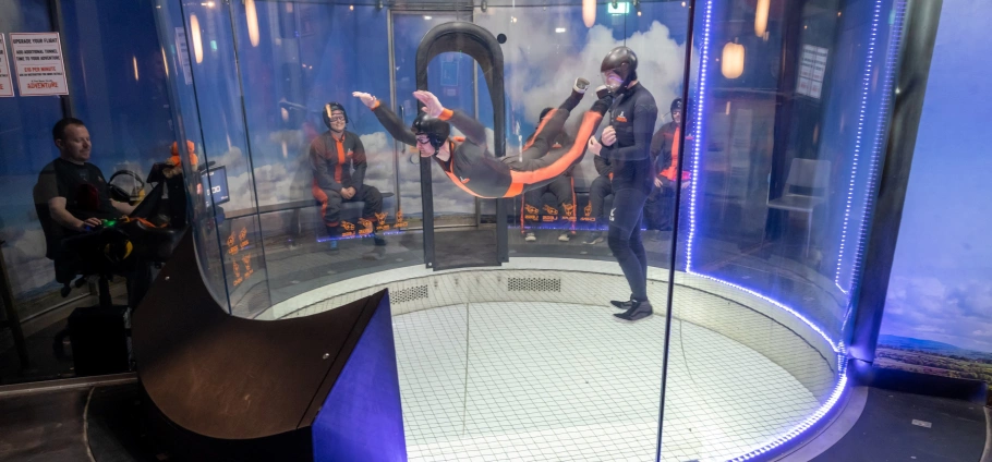 Indoor skydiving experience with instructor in wind tunnel simulation.