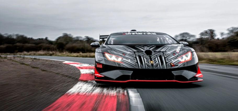 Ultimate Motorsports Race Day Experience in London | Race car speeding on a track with a dramatic front view, showcasing aerodynamic design and vibrant decals.