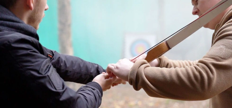 Archery instructor teaching a student how to hold and aim a bow and arrow at  the Woodland Archery Experience Near Birmingham