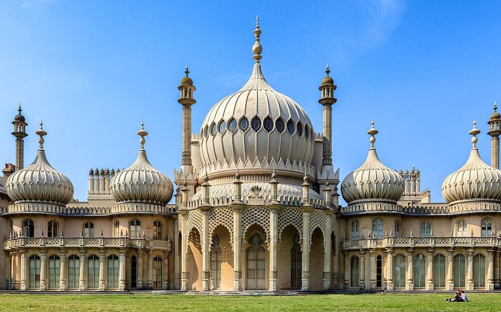 Front view of the Royal Pavilion in Brighton, England, featuring its distinctive Indo-Saracenic architecture with large onion-shaped domes and minarets against a clear blue sky